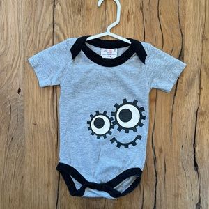 Sckoon. Size 6-12 months. Grey, silly smily face, onesie.